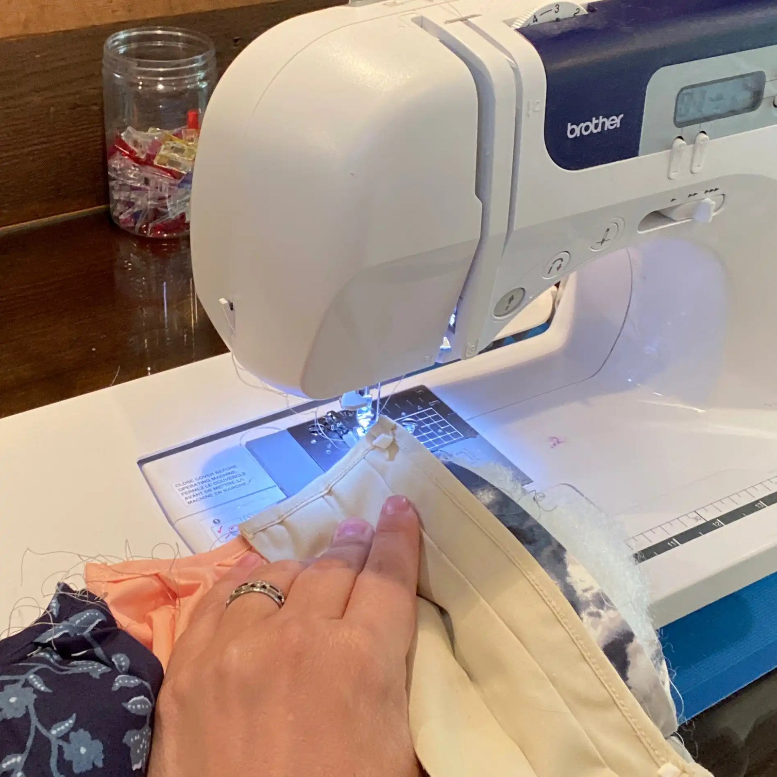 A white and blue Brother sewing machine in use.